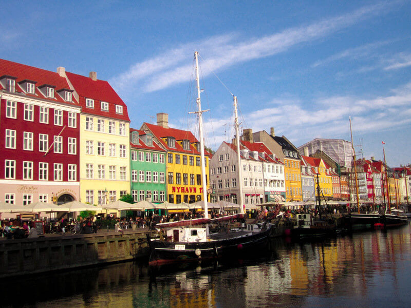 the famous nyhavn harbor in Copenhagen during summertime is a must see on your Copenhagen trip